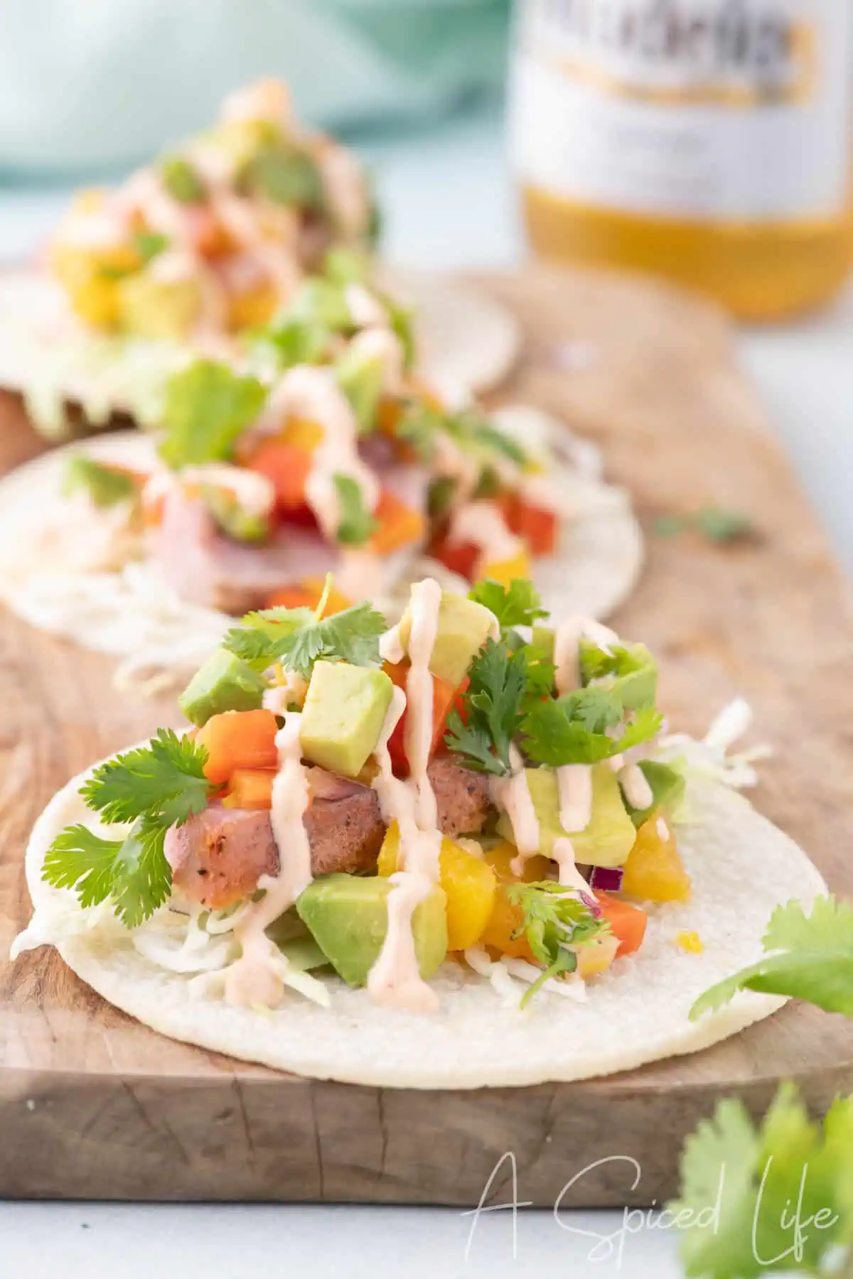 Overhead view of ahi tuna tacos with mango papaya salsa, avocado, cilantro, lime, and creamy sriracha sauce