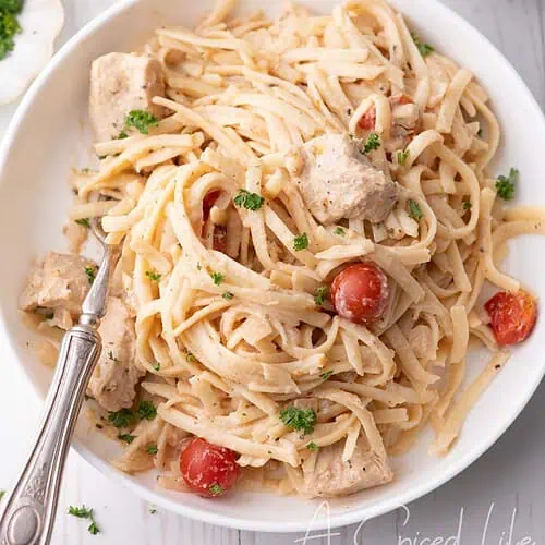 Overhead view of chicken spaghetti in a white bowl with herbs and tomatoes