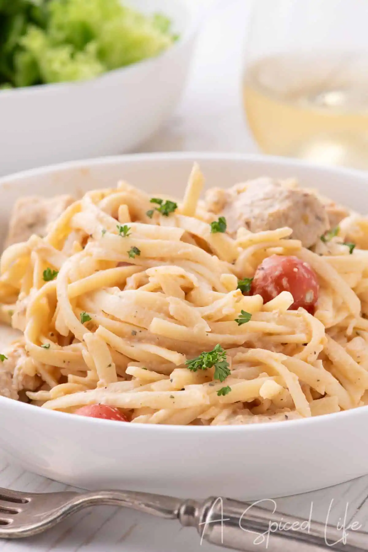 Creamy chicken spaghetti served with salad and white wine on the side