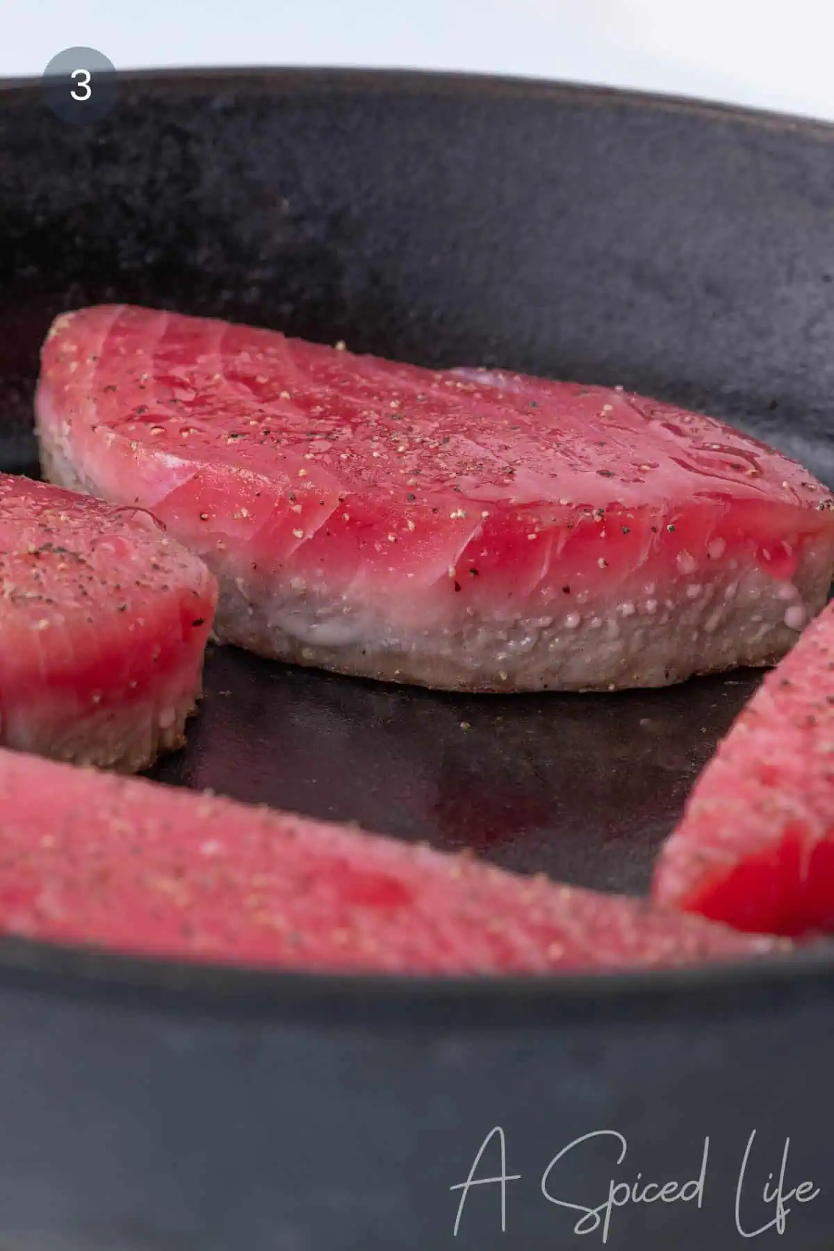 Ahi tuna steaks searing in a hot skillet