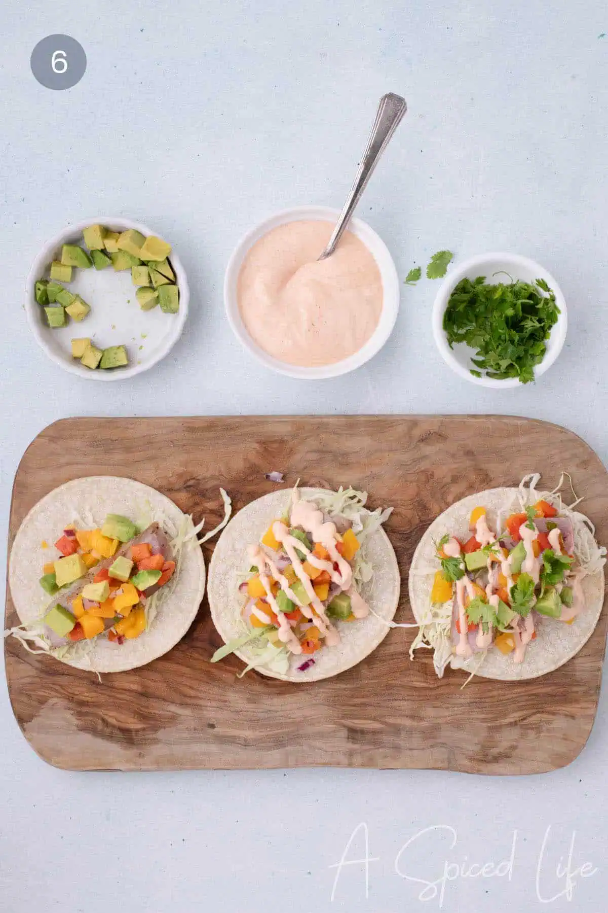 Finished seared ahi tuna tacos topped with avocado and sriracha sauce