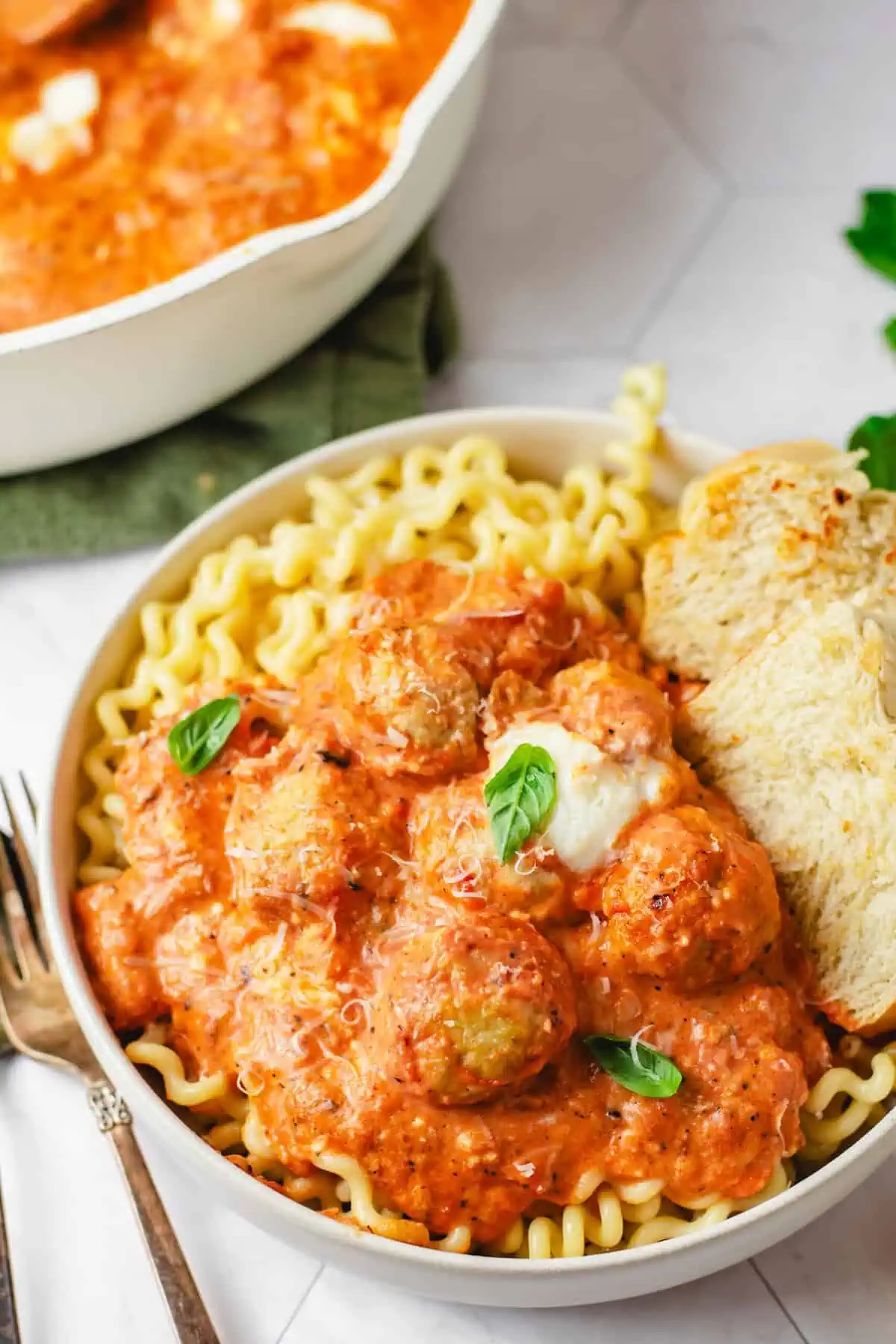 Chicken and ricotta meatballs served over curly pasta with creamy fire-roasted tomato sauce, fresh basil, Parmesan, and crusty bread.