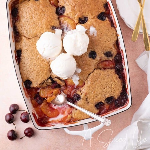 Overhead view of easy cherry peach cobbler with three scoops of ice cream on top
