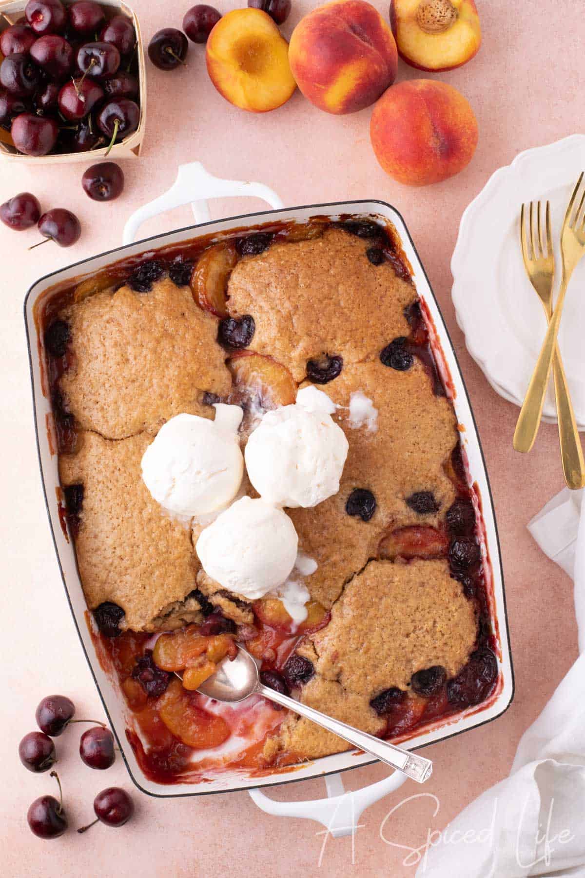 Overhead view of easy cherry peach cobbler with three scoops of ice cream on top