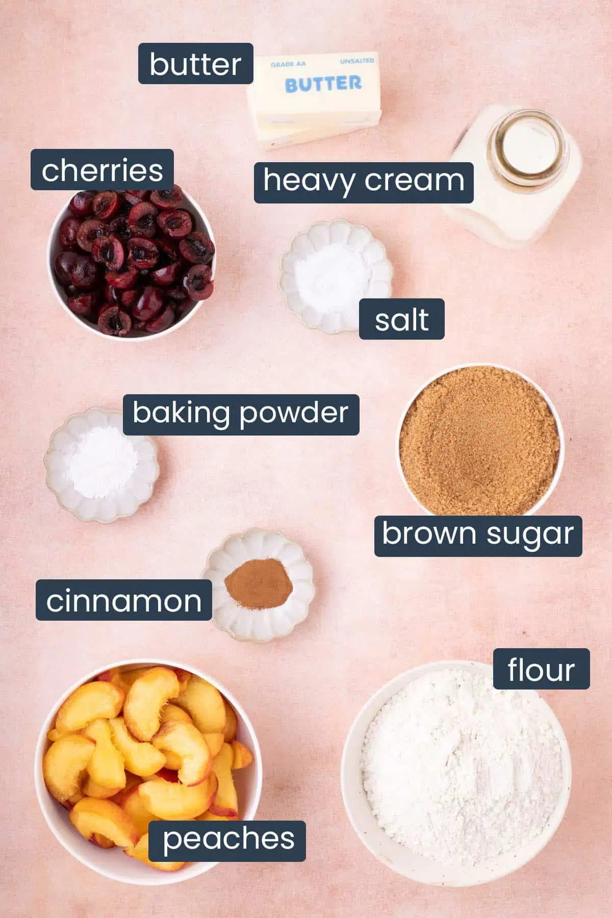 Ingredients for cherry peach cobbler including peaches, cherries, flour, brown sugar, butter, heavy cream, cinnamon, baking powder, and salt