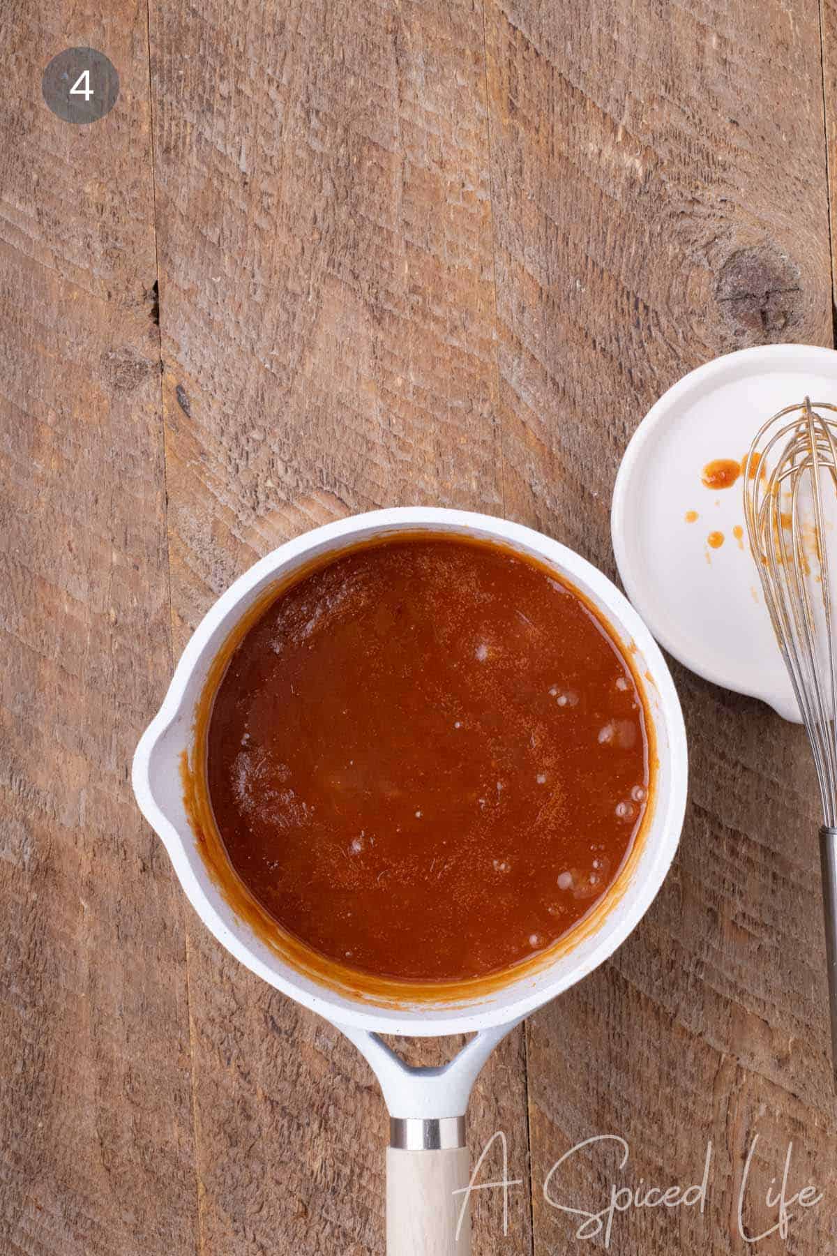 Fruity BBQ sauce simmering in a saucepan until thickened