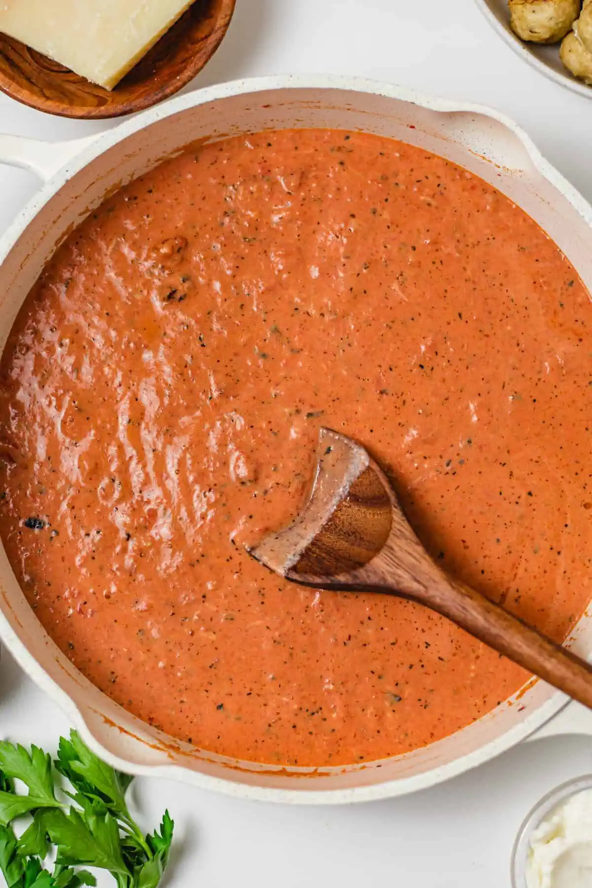 Creamy fire-roasted tomato sauce simmering in a skillet with a wooden spoon.