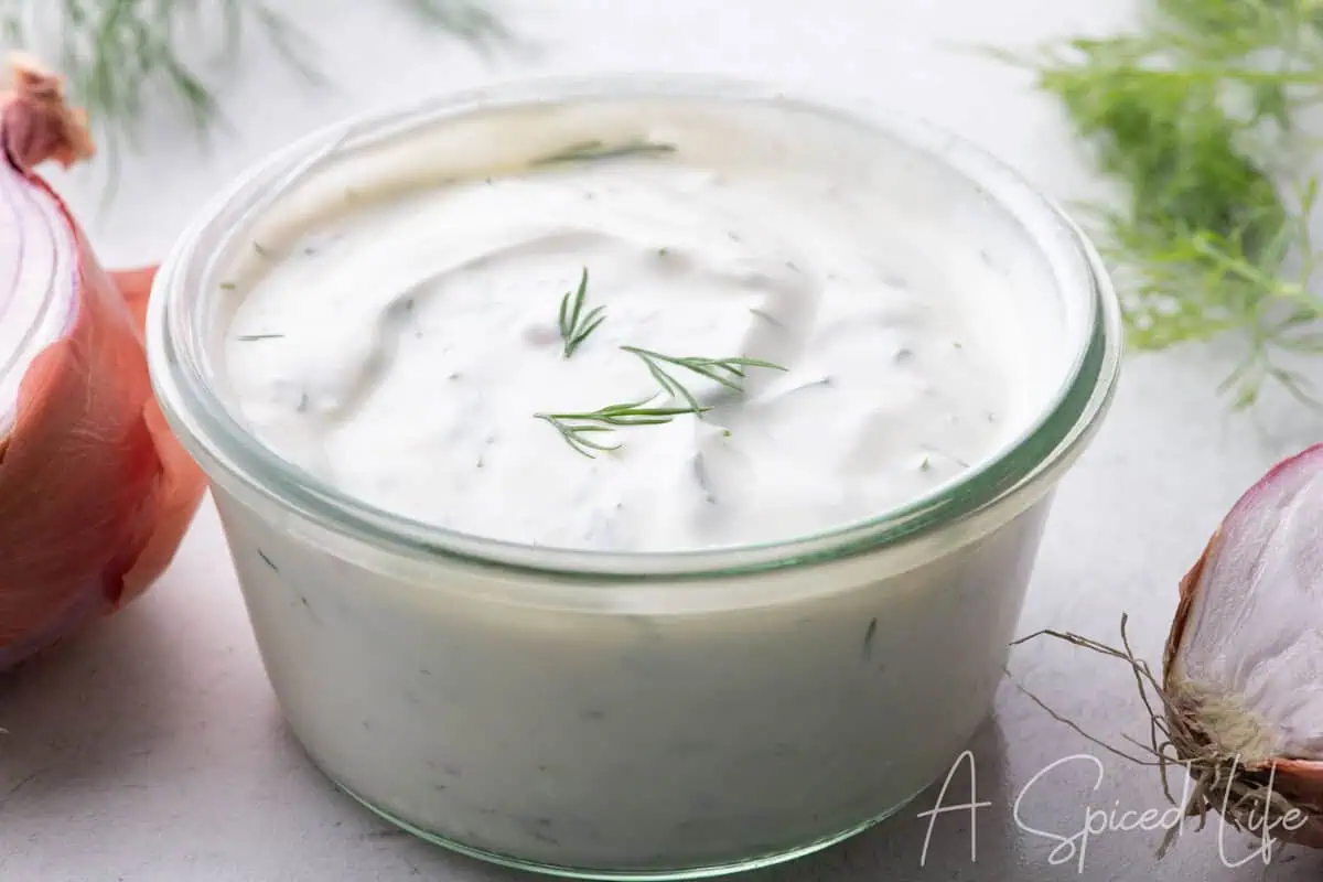 Greek yogurt dill dip in a glass bowl with fresh dill and shallots