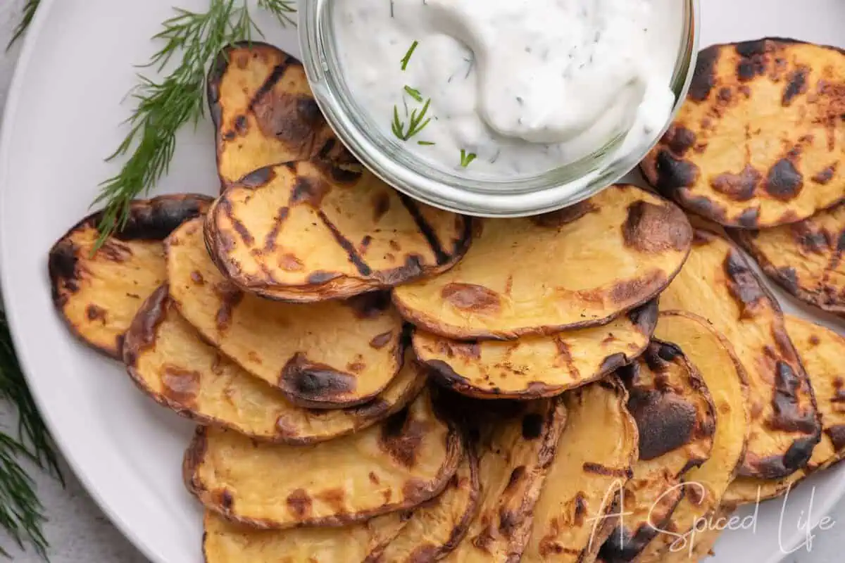 Grilled potato slices served on a platter with creamy Greek yogurt dill dip.