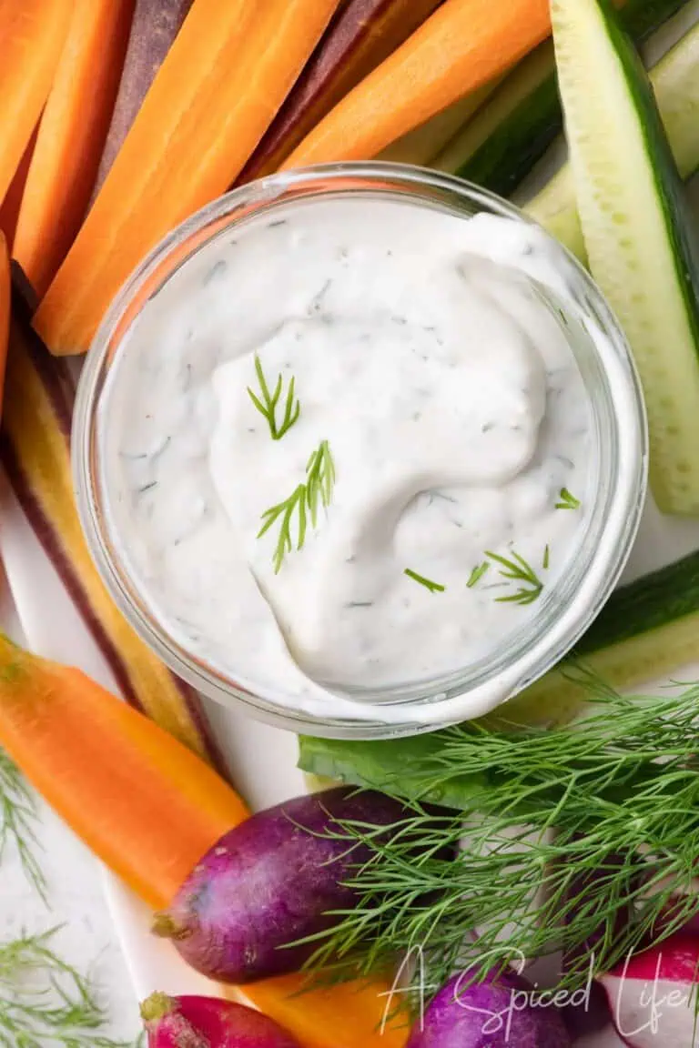 Creamy dill dip surrounded by carrots, cucumbers, radishes, and fresh dill