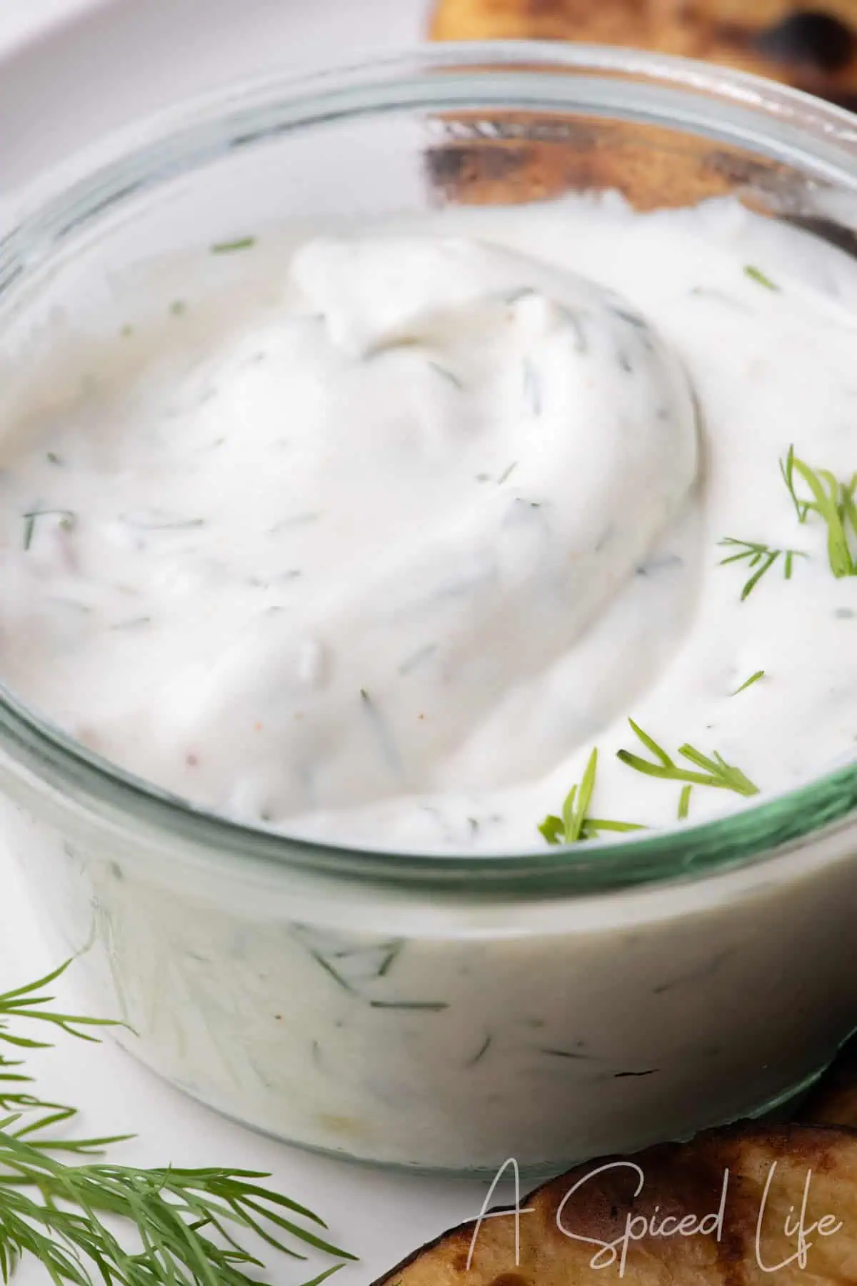 Creamy dill yogurt dip garnished with fresh dill and served with grilled potatoes