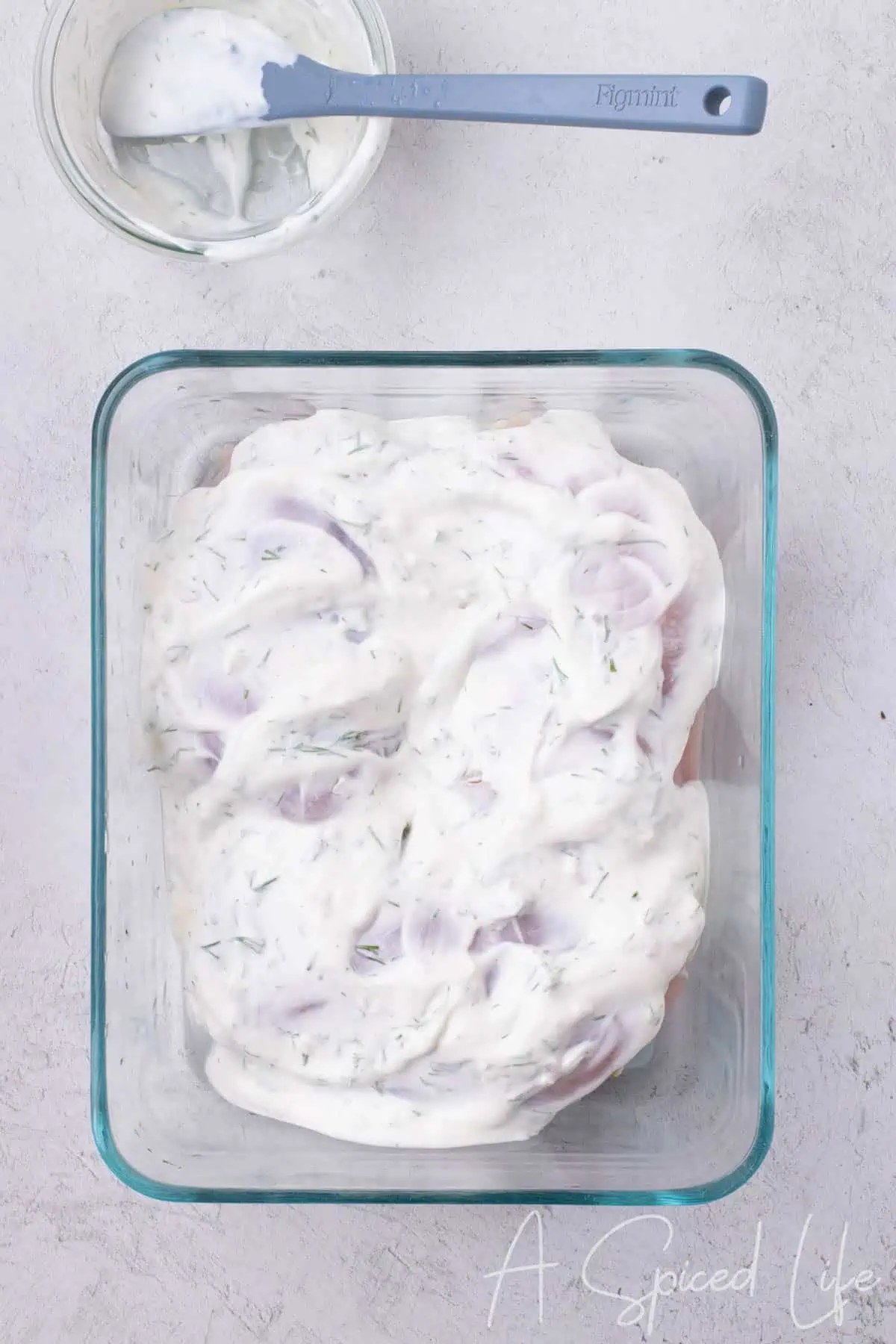 Raw chicken breasts fully coated in Greek yogurt dill marinade