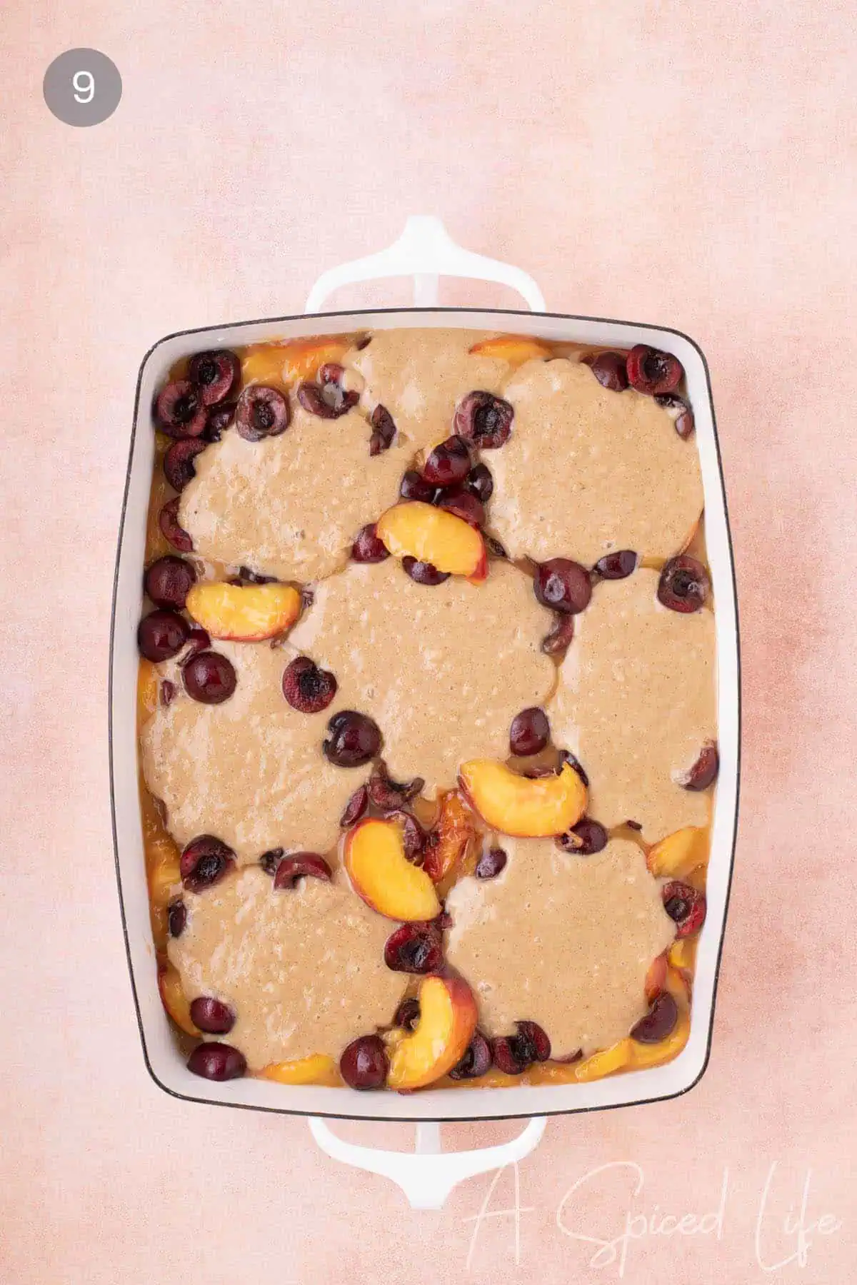 Cherry and peaches poking through the batter for the homemade cobbler dessert.