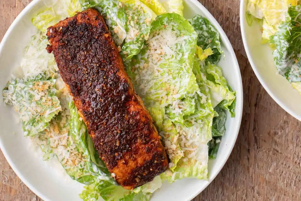 Overhead view of a blackened salmon fillet served over homemade Caesar salad.