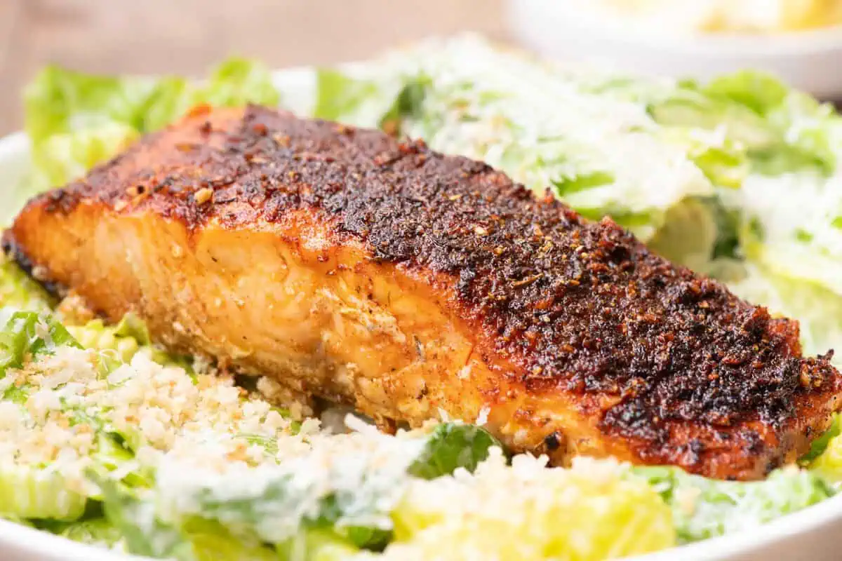 Healthy blackened salmon dinner served with Caesar salad.