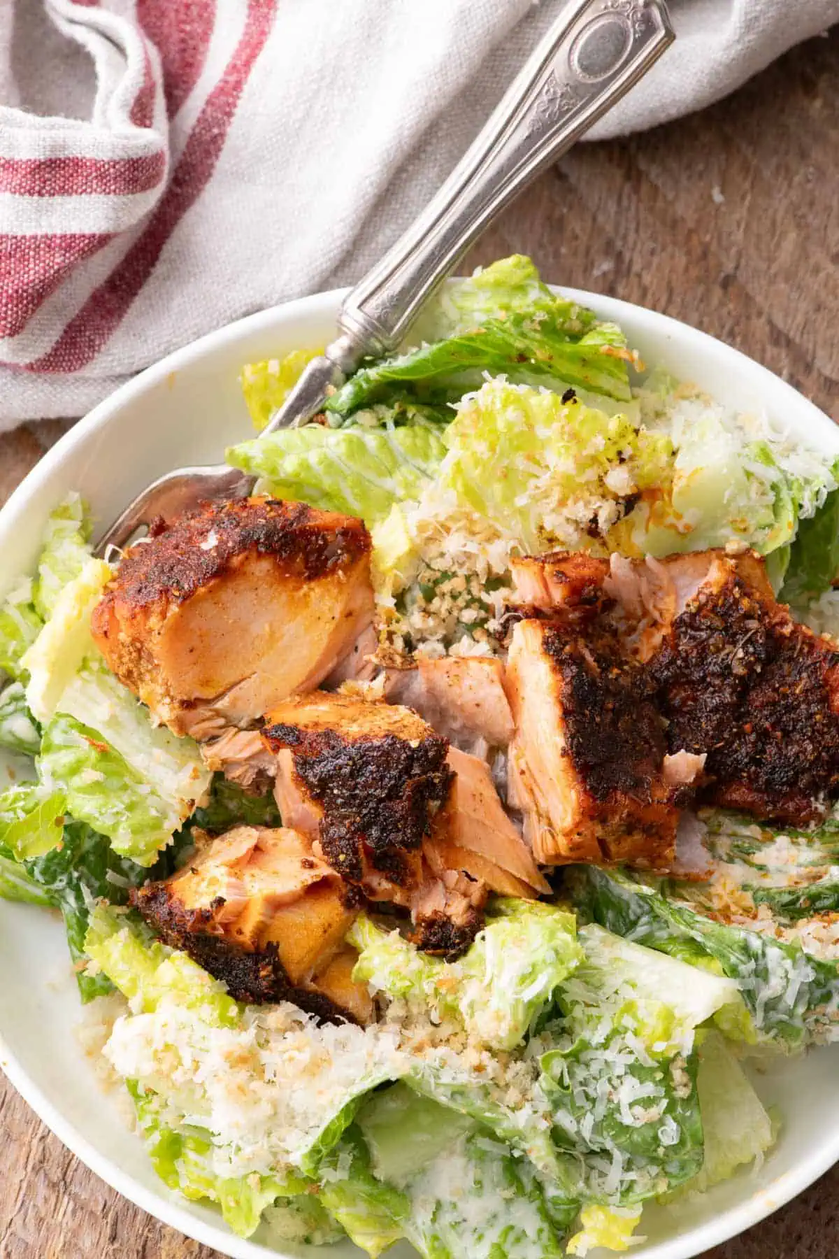 Salmon Caesar salad topped with flaked blackened salmon and Parmesan cheese.