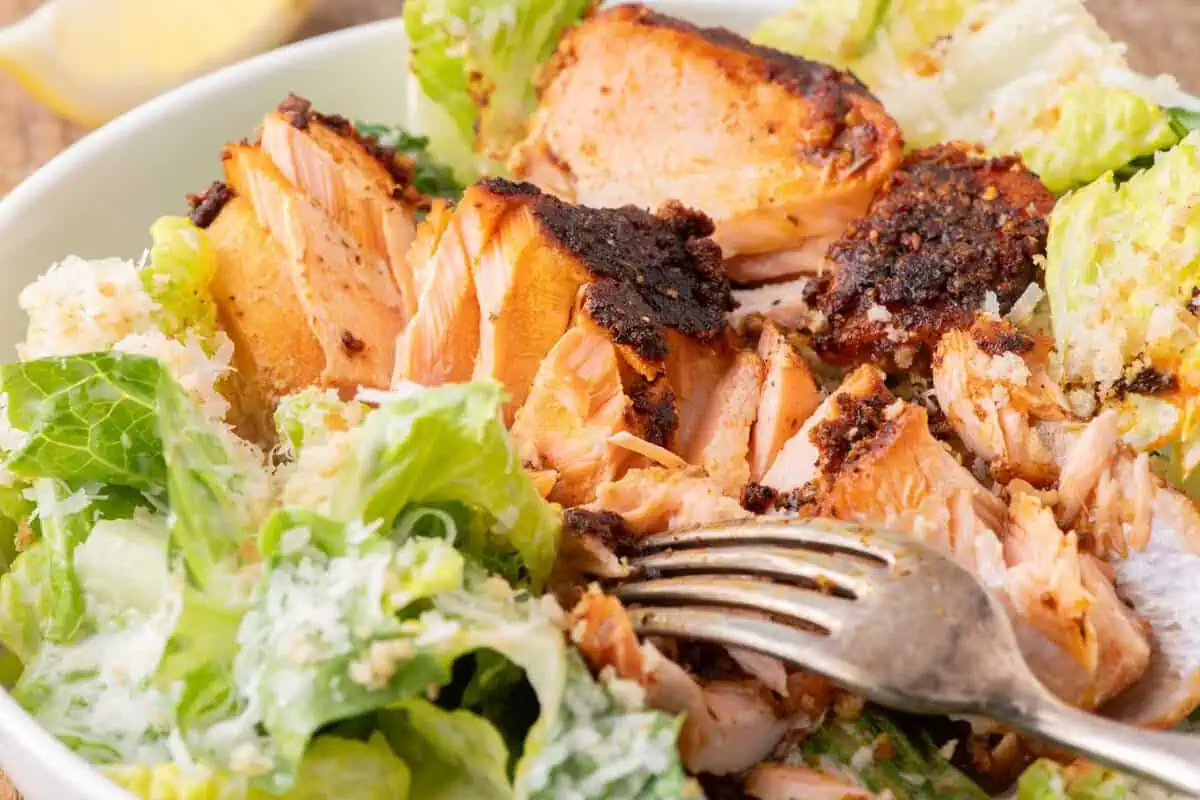 Blackened salmon with a crispy crust served over a Caesar salad.