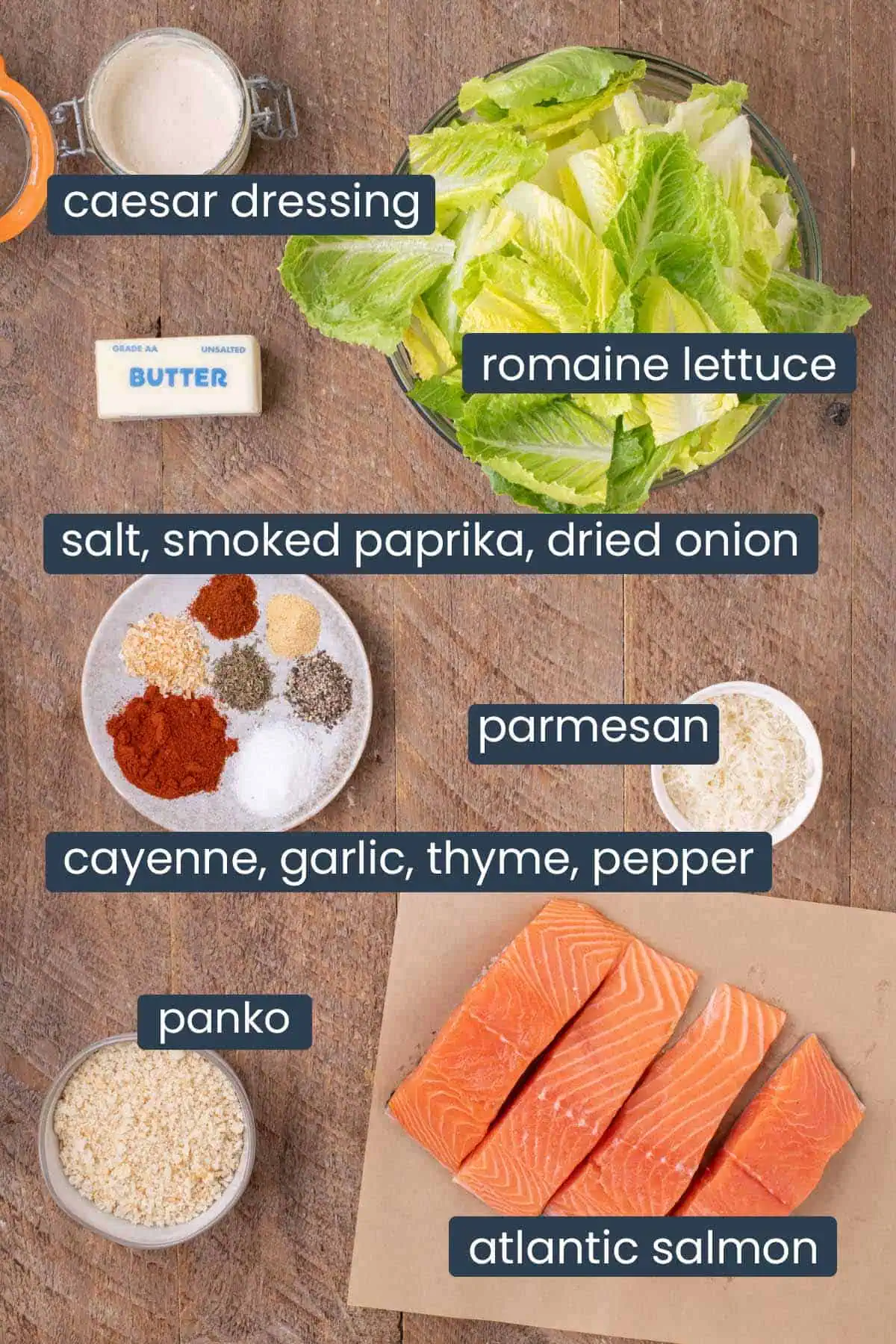 Ingredient photo for Blackened Salmon Caesar Salad showing skin-on Atlantic salmon, romaine lettuce, Caesar dressing, panko breadcrumbs, Parmesan cheese, butter, and the spices used to create the blackened salmon seasoning.