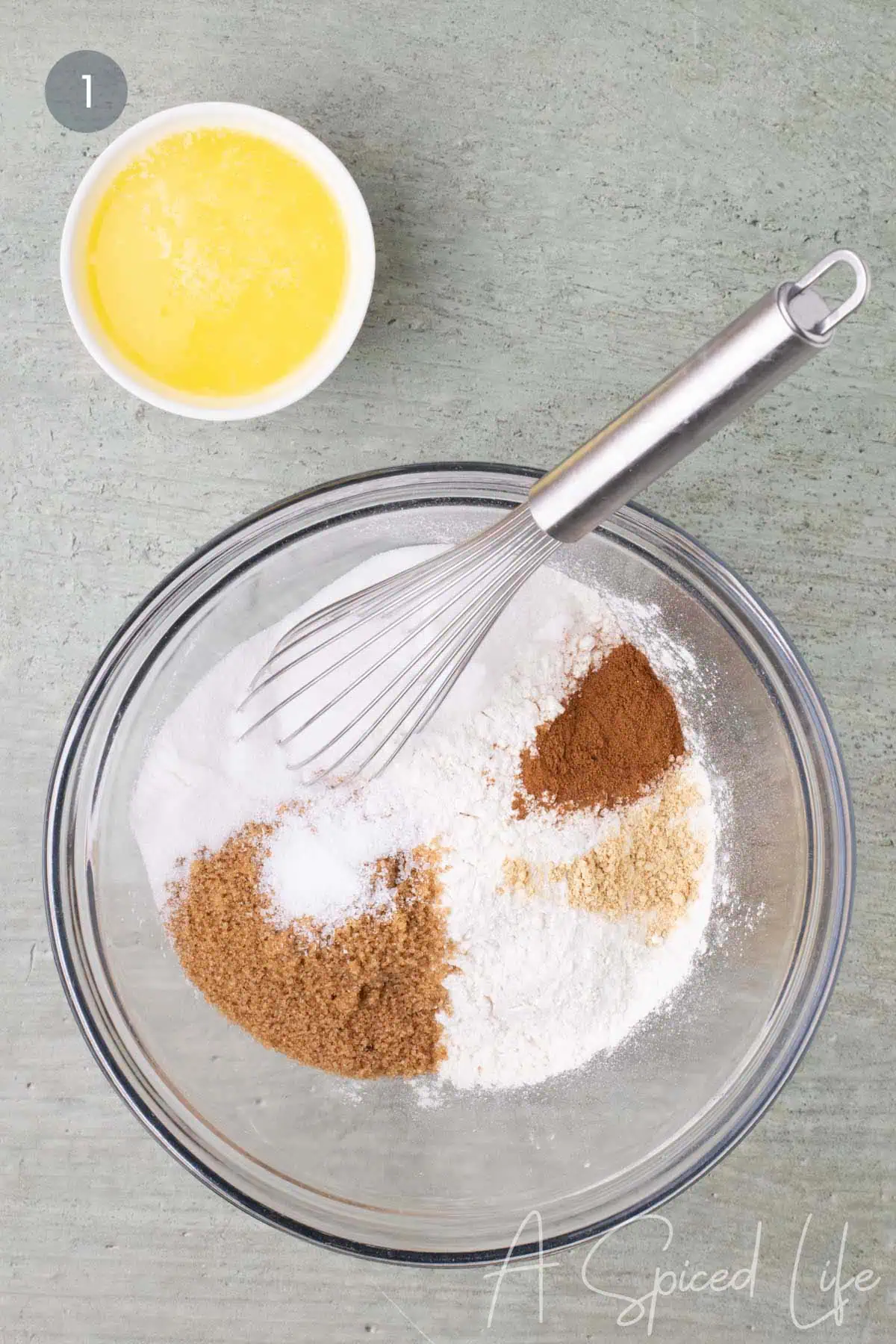 Dry ingredients for the crumb topping in a glass mixing bowl with melted butter in a small bowl beside it.