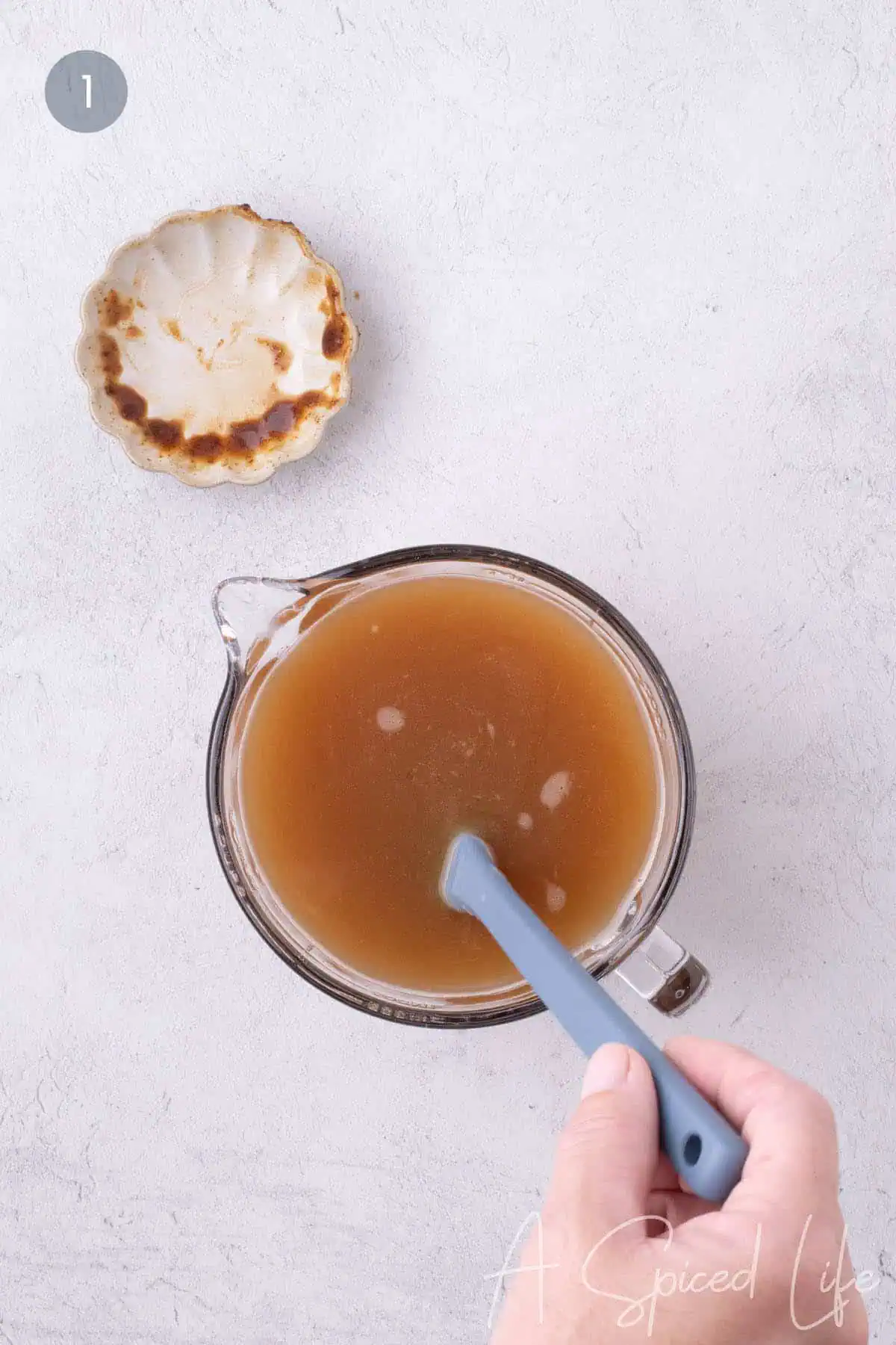 Stirring the seasoned broth mixture for grilled potato slices in a measuring jug.