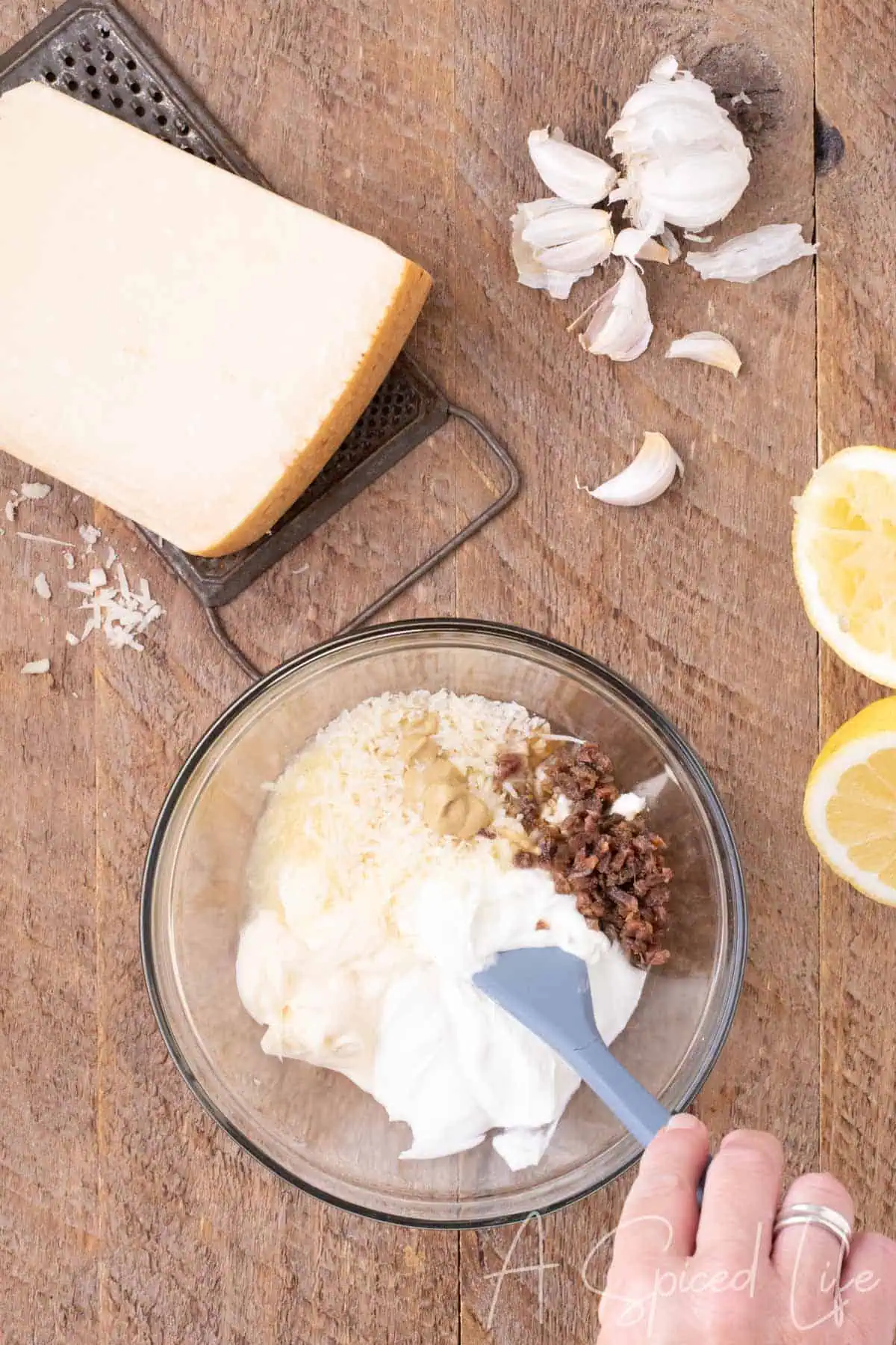 Mayonnaise, Greek yogurt, Parmesan, Dijon mustard and minced anchovies in a glass bowl for Caesar dressing.