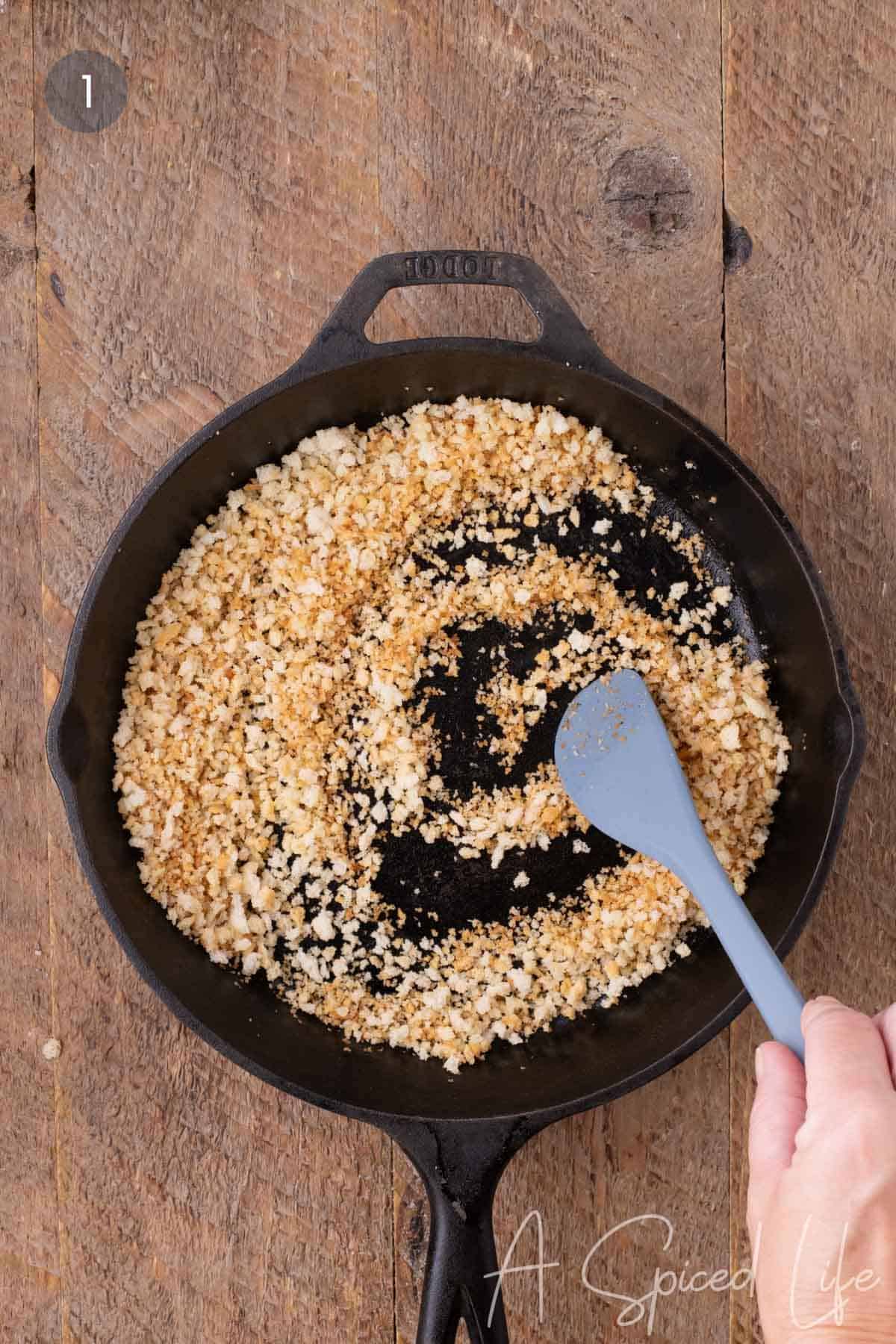 Panko breadcrumbs being toasted in butter to create a crunchy Parmesan topping for blackened salmon.