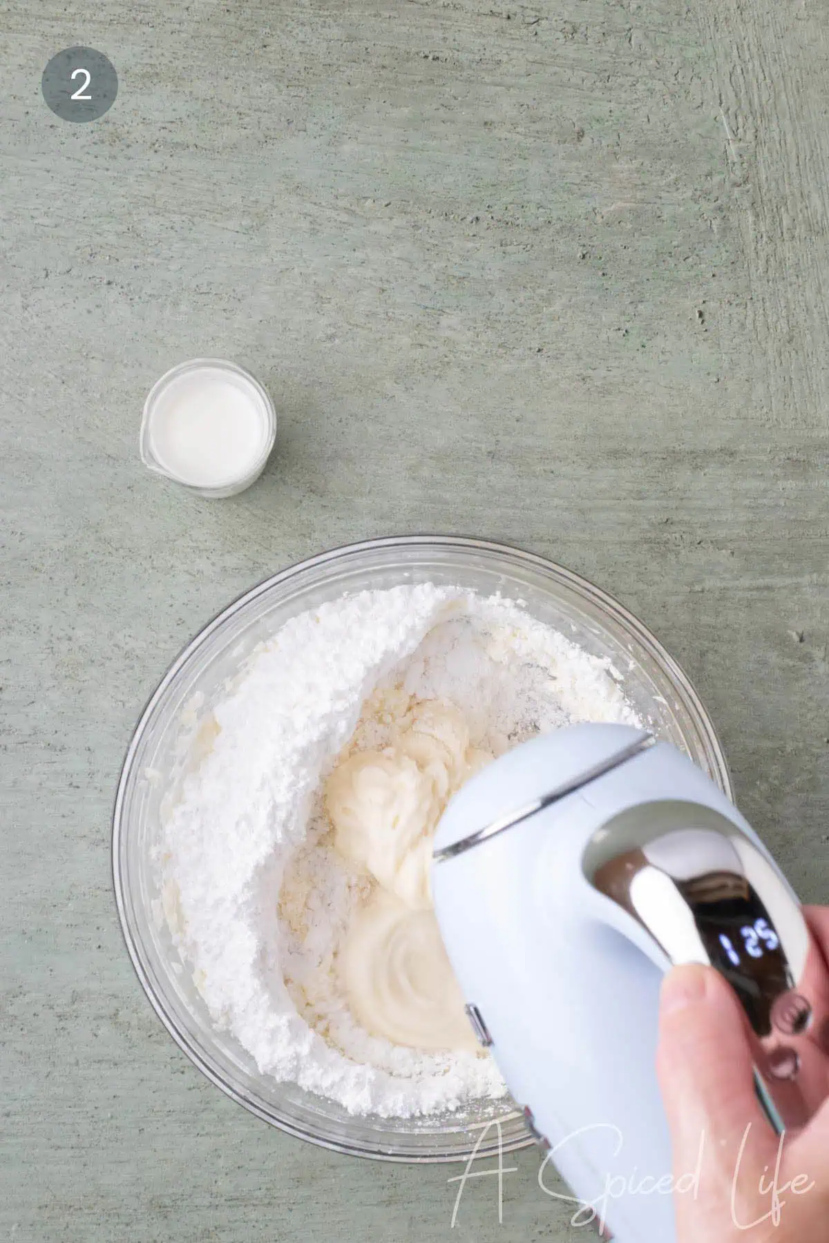 Powdered sugar being mixed into the cream cheese and butter mixture for cream cheese glaze.