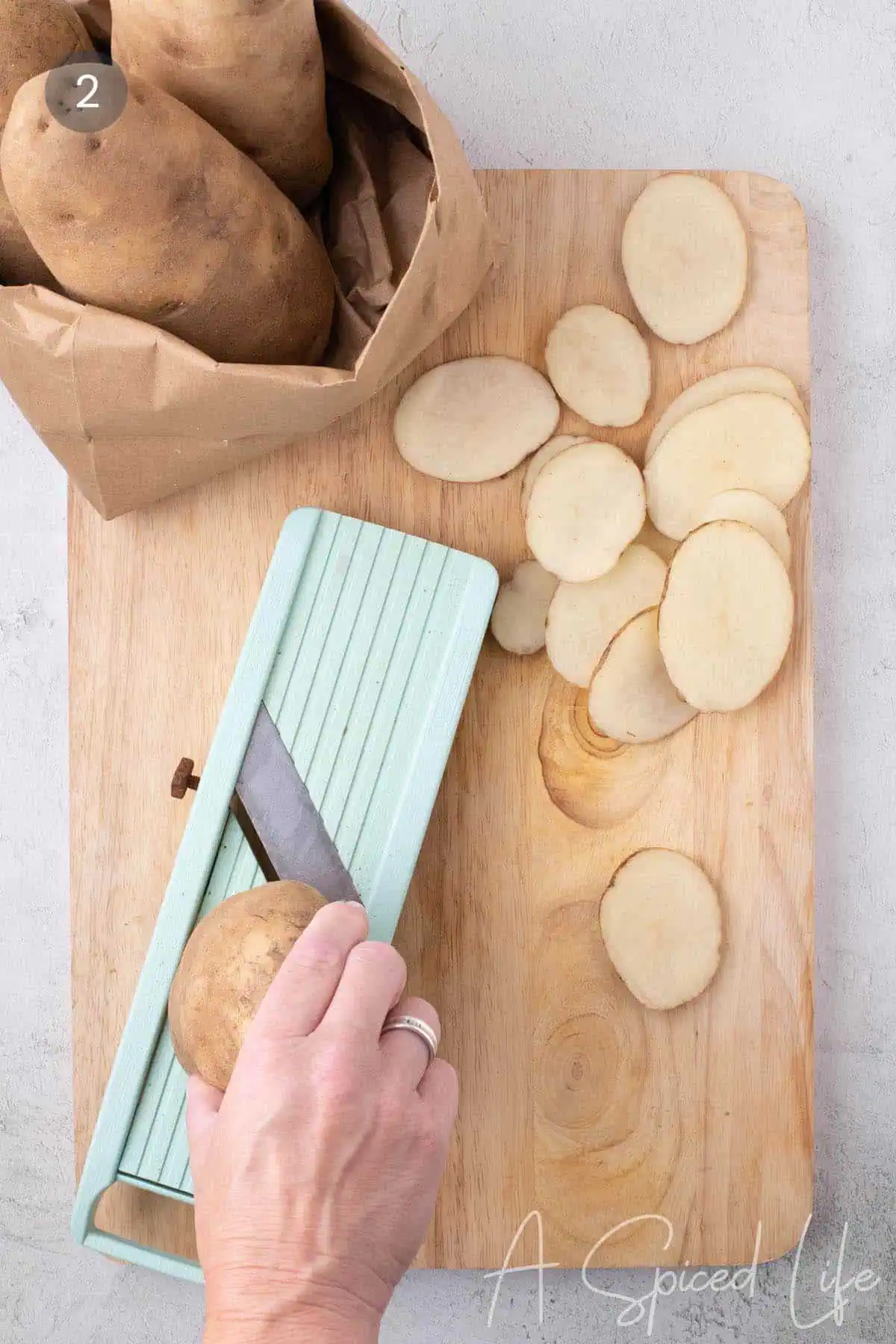 Cutting Yukon Gold potatoes into even ¼-inch slices with a mandoline for grilled potato slices.
