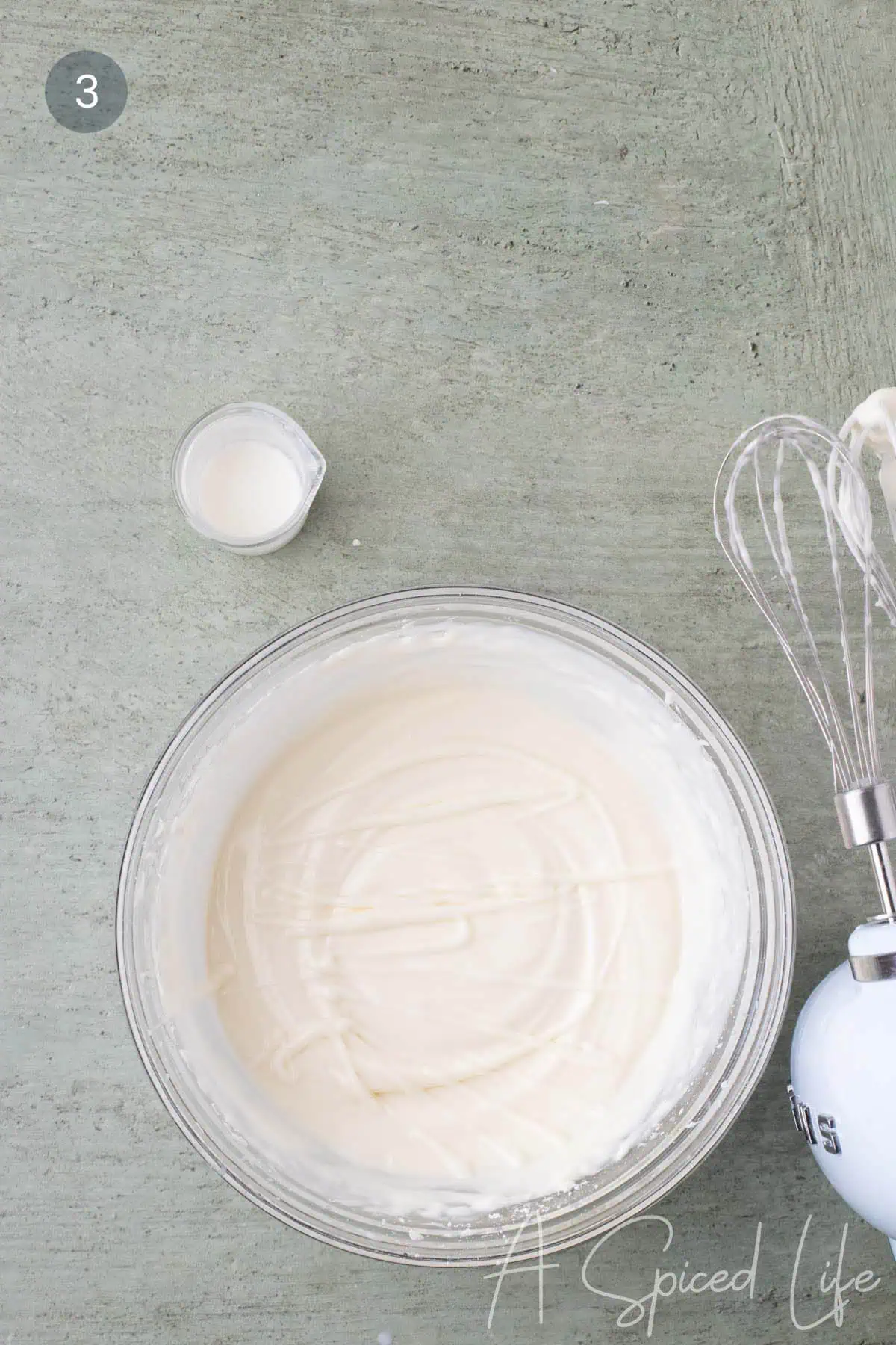Finished cream cheese glaze in a mixing bowl with a smooth, creamy consistency.
