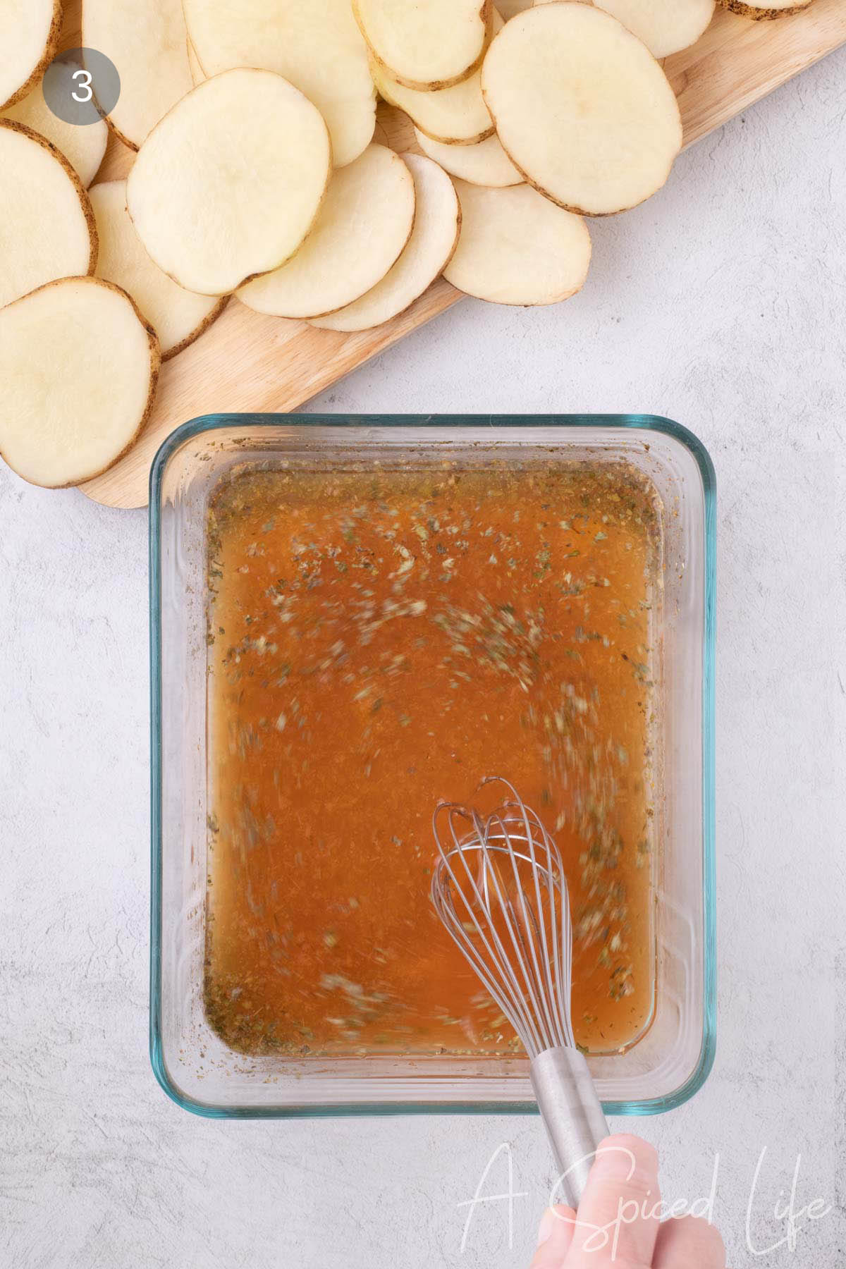 Whisking broth, lemon juice, olive oil, oregano, garlic powder, and salt in a glass container.