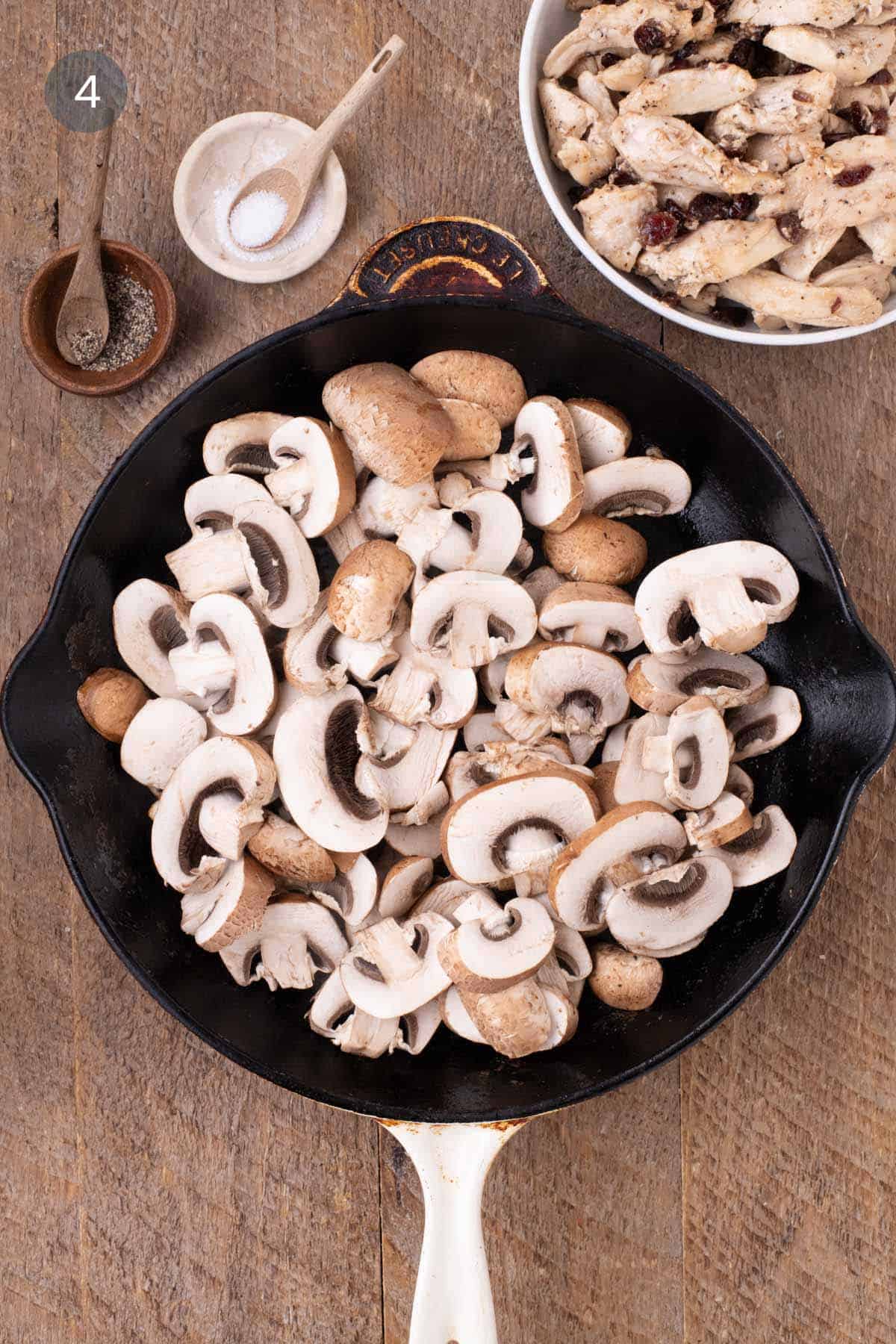 Sliced mushrooms added to a skillet after cooking the chicken for warm chicken and rice salad.