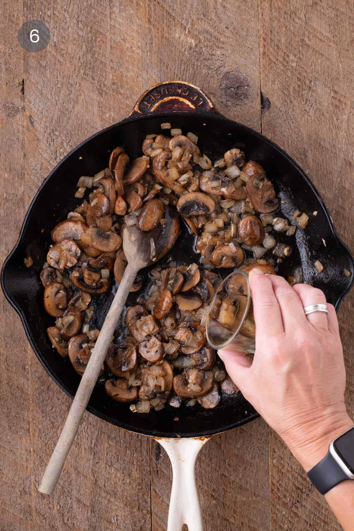 Sherry being poured into a skillet of browned mushrooms, onions, and garlic for warm chicken and rice salad.