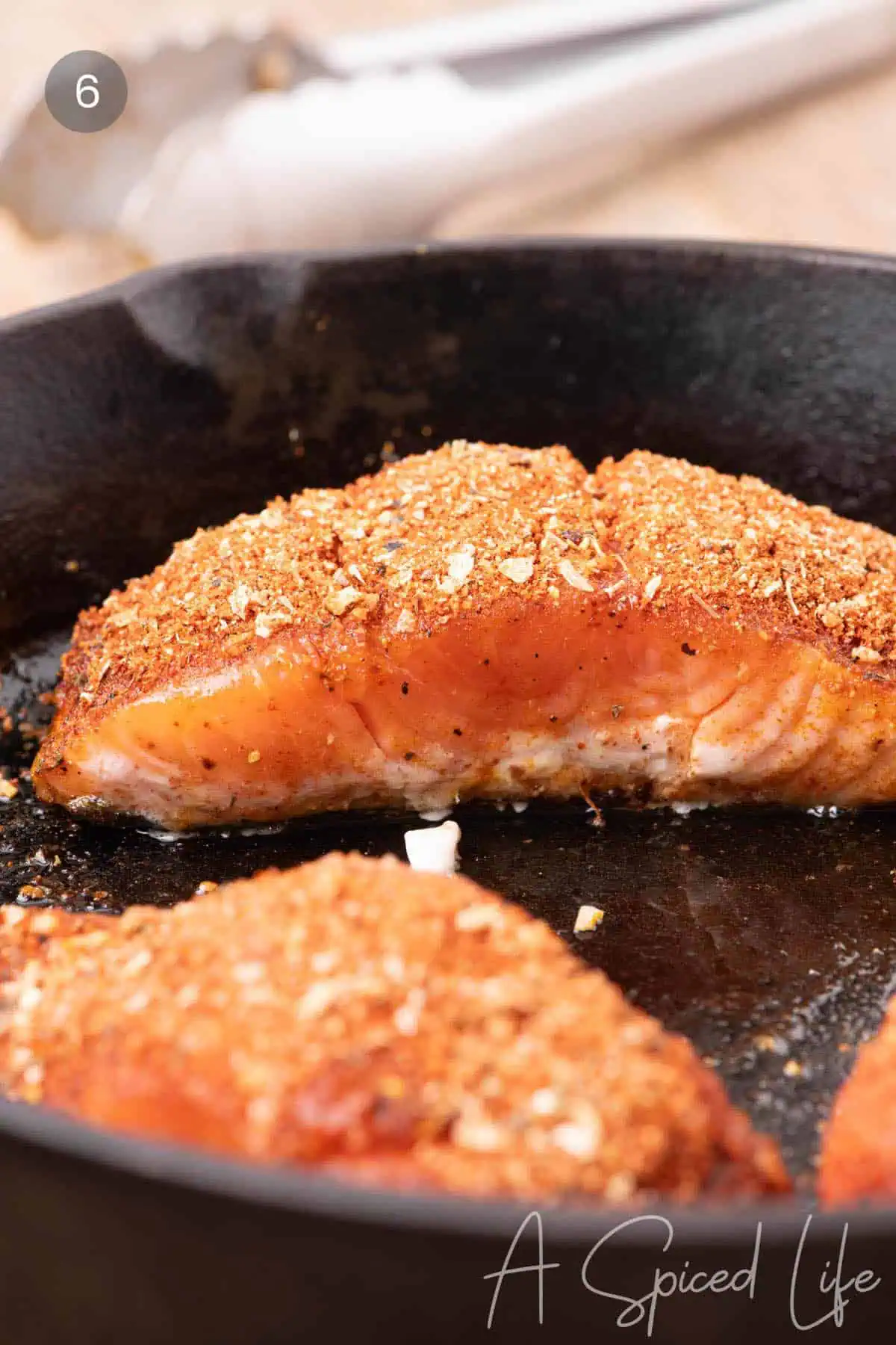 Close-up showing salmon becoming opaque as it cooks in a skillet.