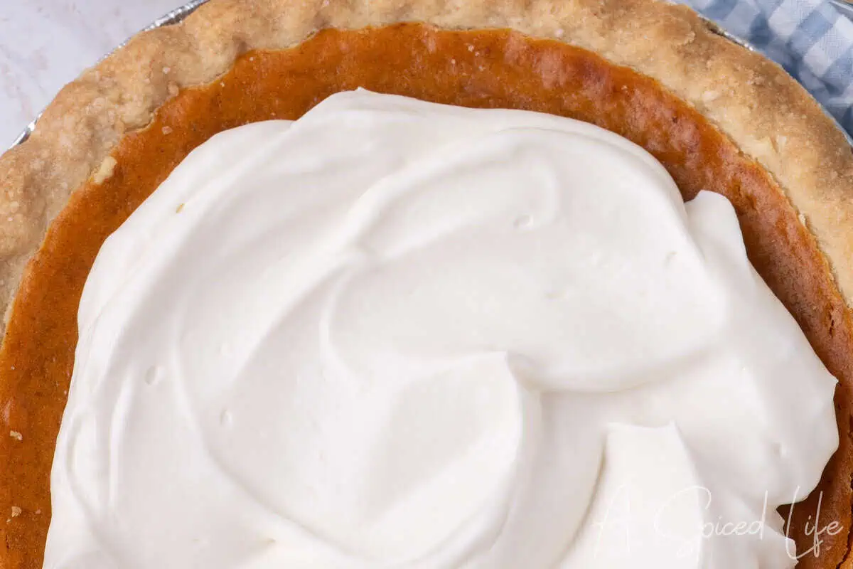 Pumpkin pie topped with a thick layer of homemade whipped cream.