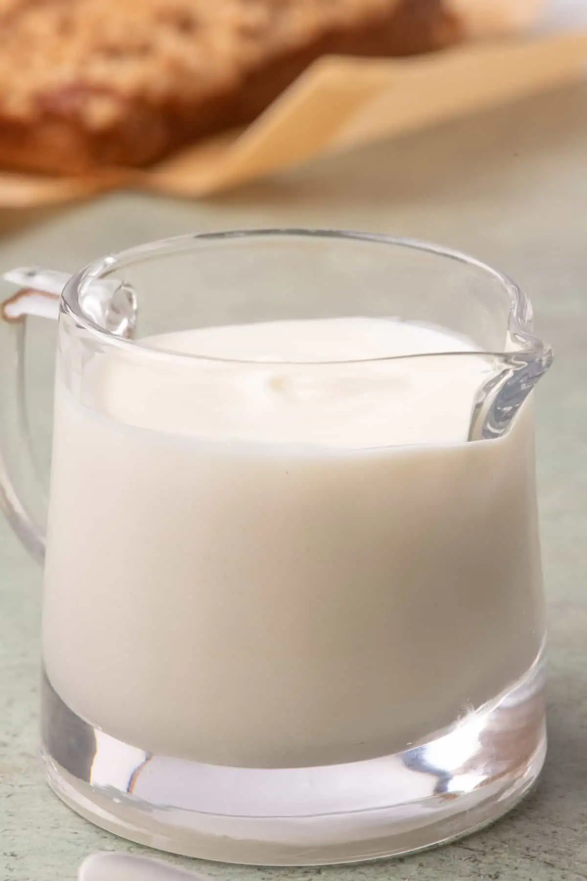 Creamy cream cheese glaze served in a clear glass pitcher.