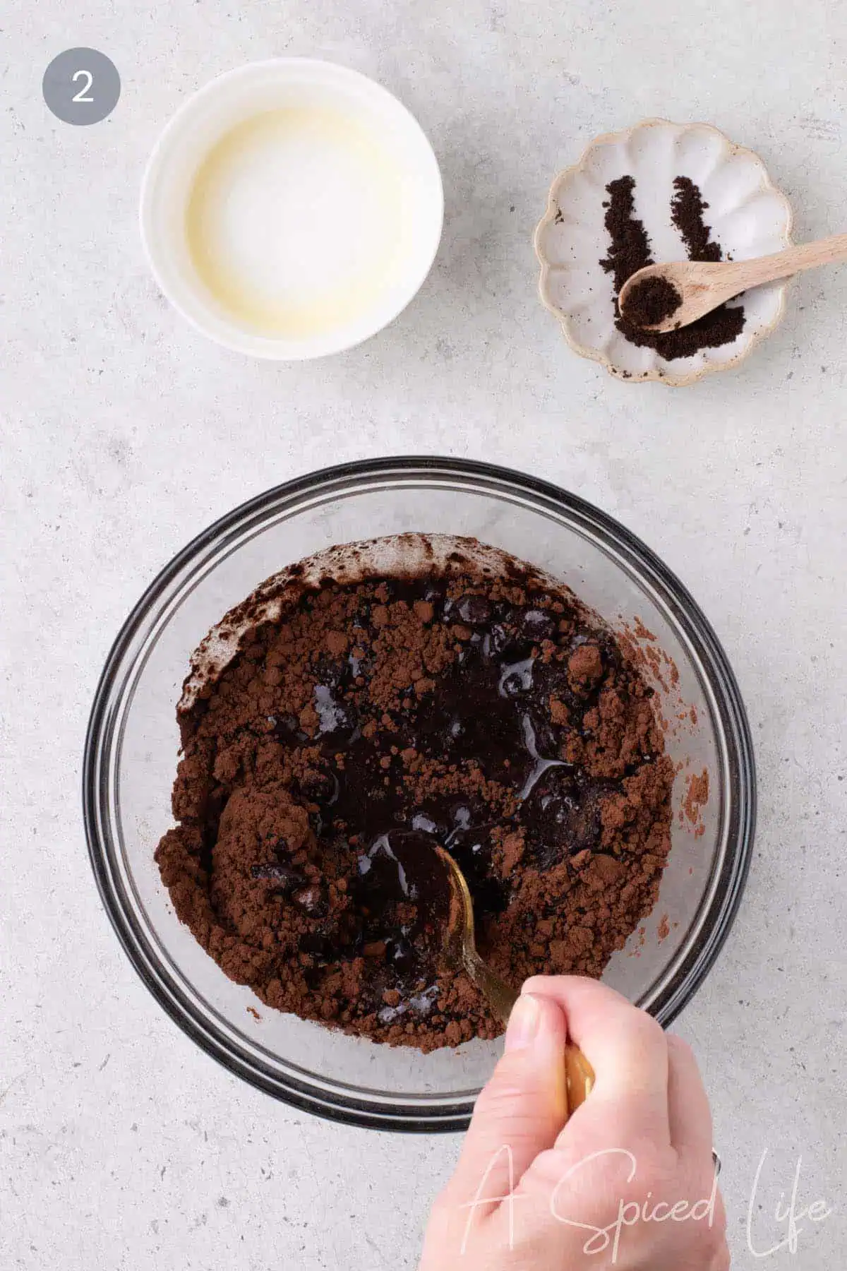 Chocolate chips, cocoa powder, espresso powder, and melted butter in a glass bowl before stirring