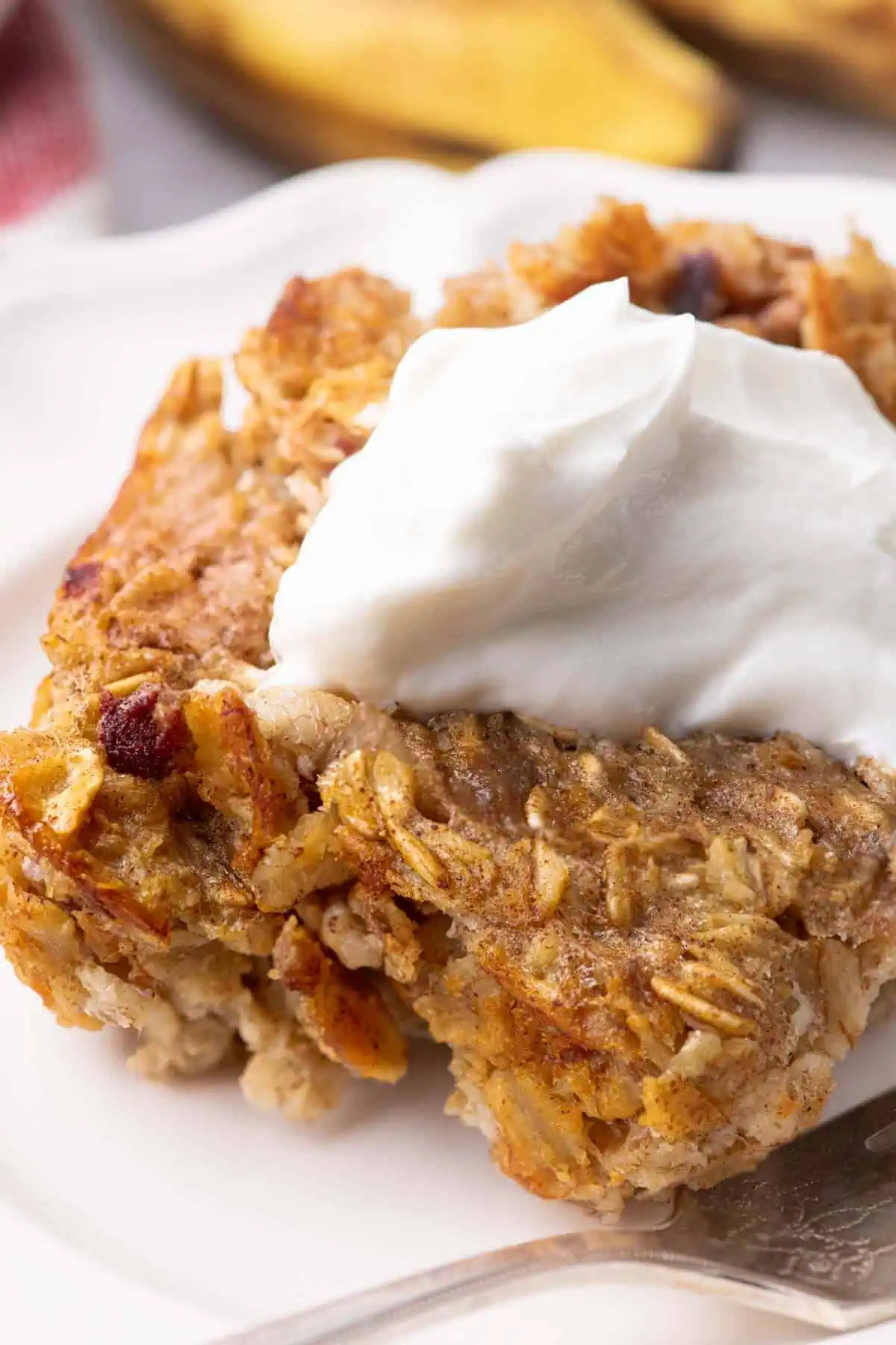 A serving of banana-and-date baked oatmeal, topped with a dollop of Greek yogurt, on a white plate.
