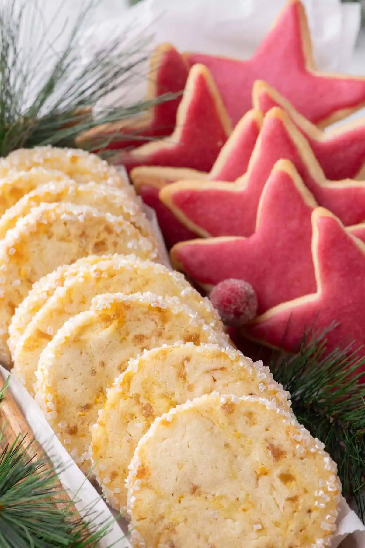 Sugar-coated orange ginger cookies beside pink cranberry-glazed star cookies